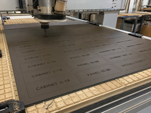 LYS-7079 thin matte brown black millwork label sheet processed on a realistic large industrial CNC spoilboard table